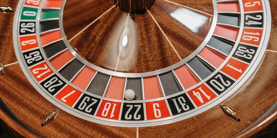 close up view of a wooden casino roulette with a white ball on black 22